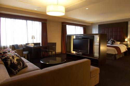 a hotel room with a couch and a television and a bed at Nagoya Tokyu Hotel in Nagoya