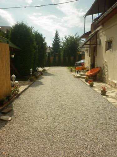 a gravel road next to a house and a building at Táltos Vendégház in Szilvásvárad