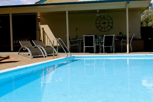 a blue swimming pool with chairs and a table at Isis Motel Scone in Scone