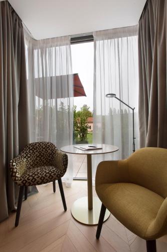 a living room with a table and a chair and a window at Villaggio Narrante - Le Case dei Conti Mirafiore in Serralunga d'Alba