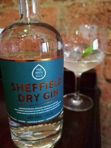 a bottle of gin sitting next to a drink at Garrison Hotel in Sheffield