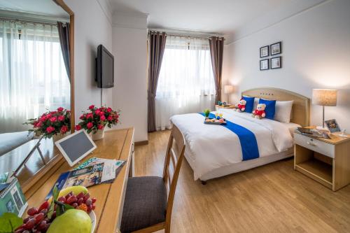 una camera d'albergo con letto, tavolo e scrivania di Rose Garden Residences a Hanoi