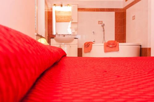 a red bed in a bathroom with a sink and a tub at Villa Cicas sul mare in Campofelice di Roccella