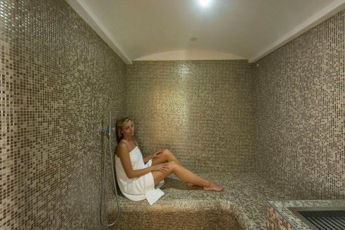 a woman sitting in a corner of a shower at Hotel Romanda in Levico Terme
