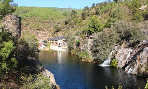 a river with a building on the side of a mountain at Alva Valley Hotel in Oliveira do Hospital