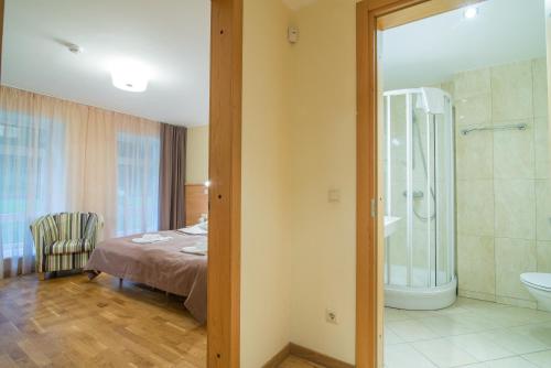 ein Schlafzimmer mit einem Bett und ein Badezimmer mit einer Dusche in der Unterkunft Guest House Milda in Druskininkai