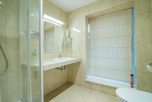 a bathroom with a shower and a sink and a toilet at Guest House Milda in Druskininkai