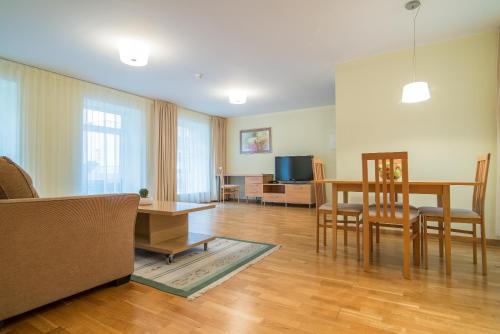 a living room with a table and chairs and a television at Guest House Milda in Druskininkai