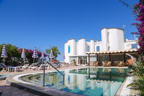 una piscina in un resort con tavoli e sedie di Hotel Loreley a Ischia