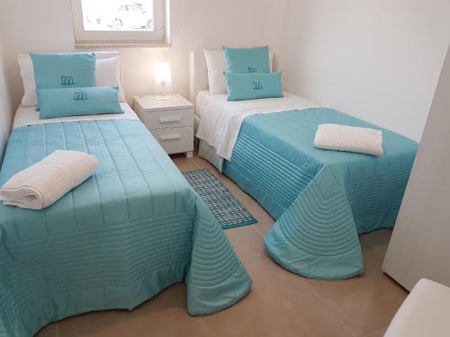 two beds in a room with blue and white at I MESTRI Holiday Homes in Uggiano la Chiesa