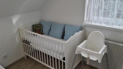 a white crib with blue pillows in a nursery at Ferienwohnung Strandwurzel in Zempin