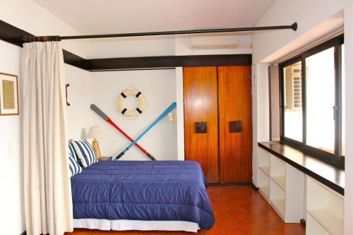 sypialnia z łóżkiem z niebieską pościelą i kijami baseballowymi na ścianie w obiekcie Akisol Sesimbra Beach w mieście Sesimbra
