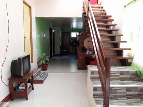 a living room with a staircase and a tv at David & Vhie Homestay-David's Guest House in El Nido