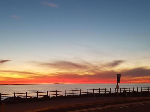 a sunset over the ocean with a fence at 210 Atlantic Sun in Bloubergstrand