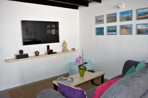 uma sala de estar com um sofá e uma televisão na parede em Apartamento Las Palmeras Nazaret em Nazaret