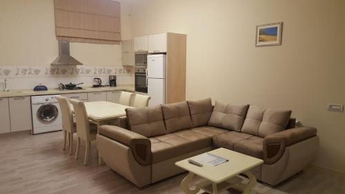 ein Wohnzimmer mit Couch und Tisch und eine Küche in der Unterkunft Charming 2 Bedroom Apartment near the City's Biggest Mall in Baku