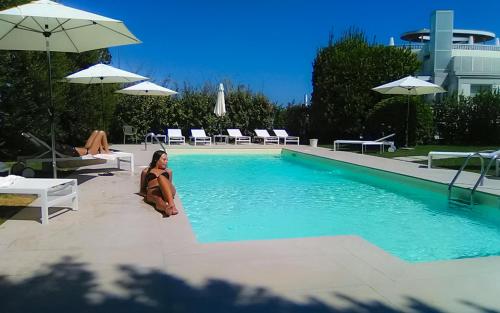 a woman is sitting next to a swimming pool at Grand Hotel Passetto in Ancona