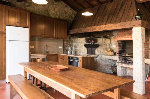 a kitchen with a wooden table and a stone wall at Casa da Pousada in Barcelos