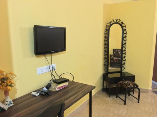 a room with a table with a tv and a mirror at John's Highland Comfort (Guest House) in Majorda