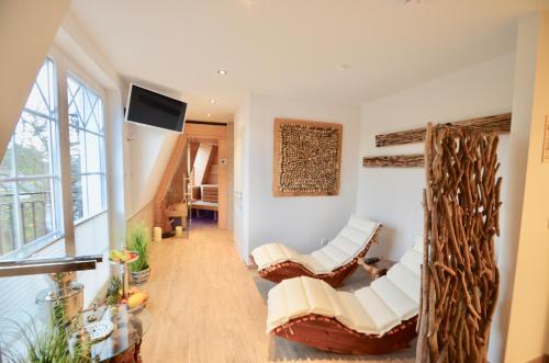 sala de estar con sillas blancas y TV en Villa Strandblick 10, en Zingst