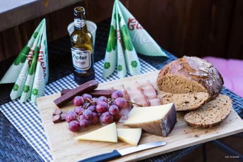 a cutting board with cheese and grapes and a bottle of beer at Natal Gian in Ischgl