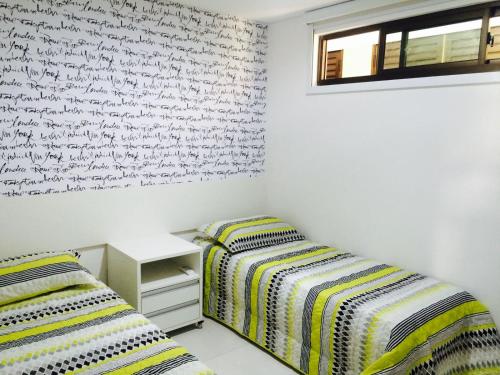 2 Betten in einem Schlafzimmer mit einer schriftlich überdachten Wand in der Unterkunft Flat Carneiros Beach Resort in Praia dos Carneiros
