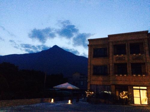 a building with a mountain in the background at Stick-On B&B in Shunan