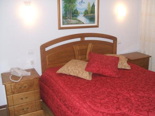 Un dormitorio con una cama roja con un teléfono. en Residencial Pinto en Guarda