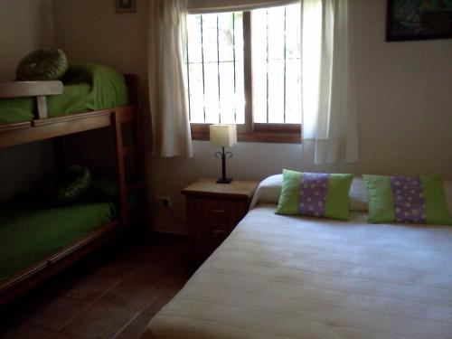a bedroom with a bed with green pillows and a window at Ñande Roga in Mar de las Pampas