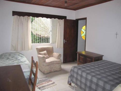 a bedroom with a bed and a chair and a window at Casa em Passa Quatro in Passa Quatro