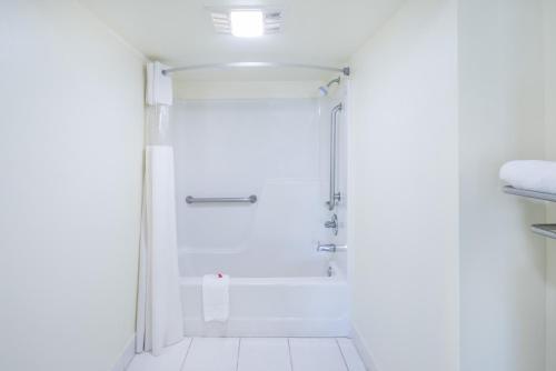 a shower in a bathroom with white walls at Days Inn by Wyndham Raleigh Midtown in Raleigh