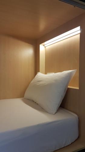 a white pillow sitting on a bed with a window at Hotel 1000 Miles in Kuala Lumpur