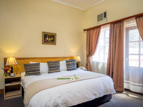 um quarto com uma cama grande e uma janela em The Elegant Lodge Menlo Park em Pretoria