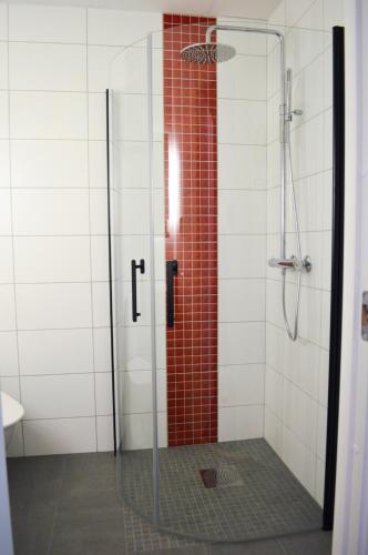 a shower with a glass door and red tile at Hotell Stortorget, Östersund in Östersund