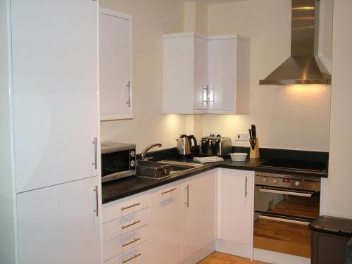 a white kitchen with white cabinets and a sink at Stratford Apartment in Newmarket