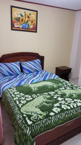 a bed with a green and white blanket on it at Nuevo Horizonte in Pasto