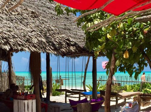 a beach with a straw umbrella and the ocean at Zanzistar Lodge in Jambiani