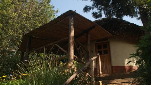 a small white house with a thatched roof at Amasiko Homestay Lake Bunyonyi in Kabale