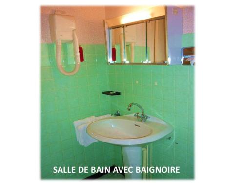 a green tiled bathroom with a sink and a mirror at La Darentasia in La Léchère