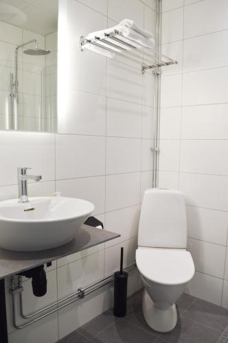 a white bathroom with a toilet and a sink at Hotell Stortorget, Östersund in Östersund