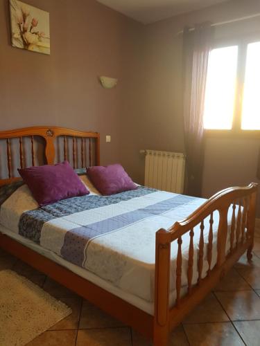 ラ・セーヌ・シュル・メールにあるVilla seynoiseのベッドルーム1室(木製ベッド1台、紫色の枕付)