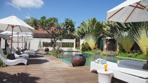 a pool with white lounge chairs and umbrellas at Katala Suites and Villas in Sanur