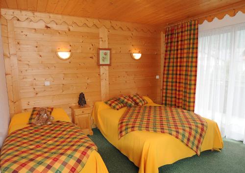 Duas camas num quarto com paredes de madeira em Résidence Les Glaciers em Samoëns
