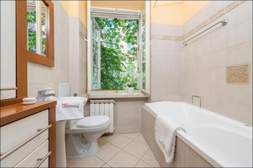 ワルシャワにあるP&O Apartments Piwnaのバスルーム(バスタブ、トイレ付)、窓が備わります。