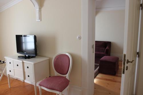 a room with a tv on a dresser and a chair at Parador Casa Da Insua in Penalva do Castelo