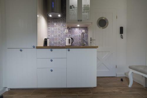 a kitchen with white cabinets and a tile wall at Blue Boat Apartment Sopot in Sopot