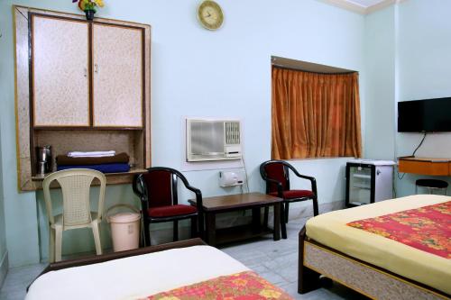 a hotel room with two beds and a table and chairs at Hotel Suriyapriya in Cuddalore