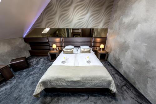 een slaapkamer met een groot bed met 2 nachtkastjes bij Royal Apartments Hotel Kecskemét in Kecskemét