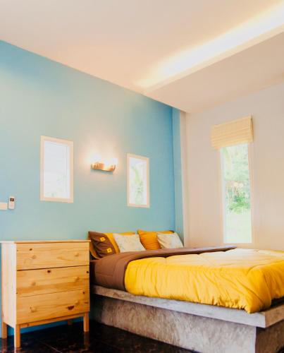 a bedroom with a bed and a blue wall at Kiri Tawan in Baan Tai