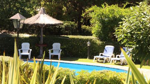 a group of chairs and an umbrella next to a pool at Terrazas de Cruz Chica. in La Cumbre